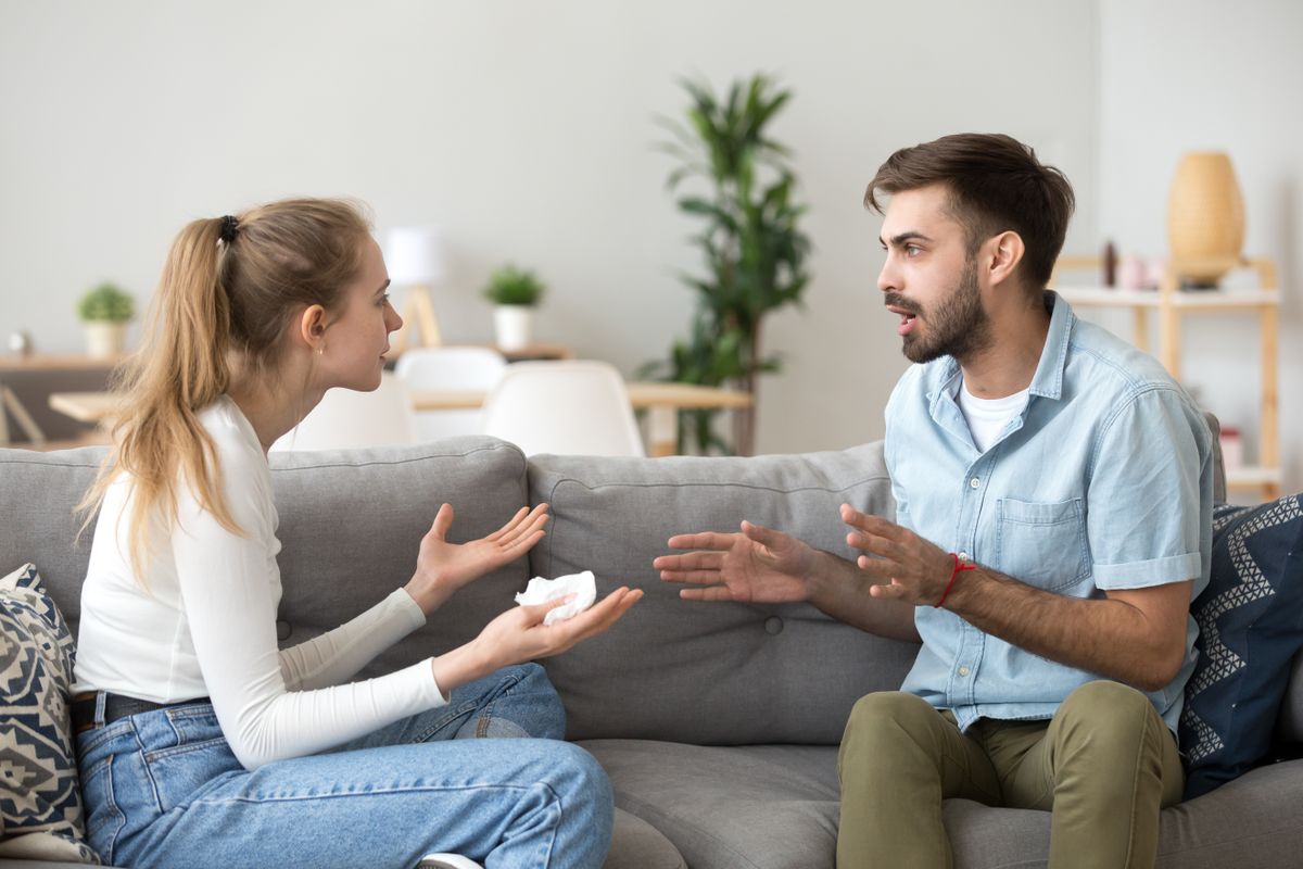 Unhappy,Young,Millennial,Married,Couple,Sitting,On,Couch,In,Living