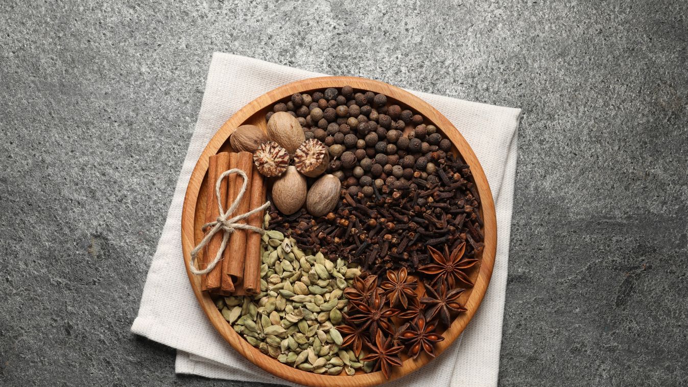 Different spices and nuts on gray textured table, top view