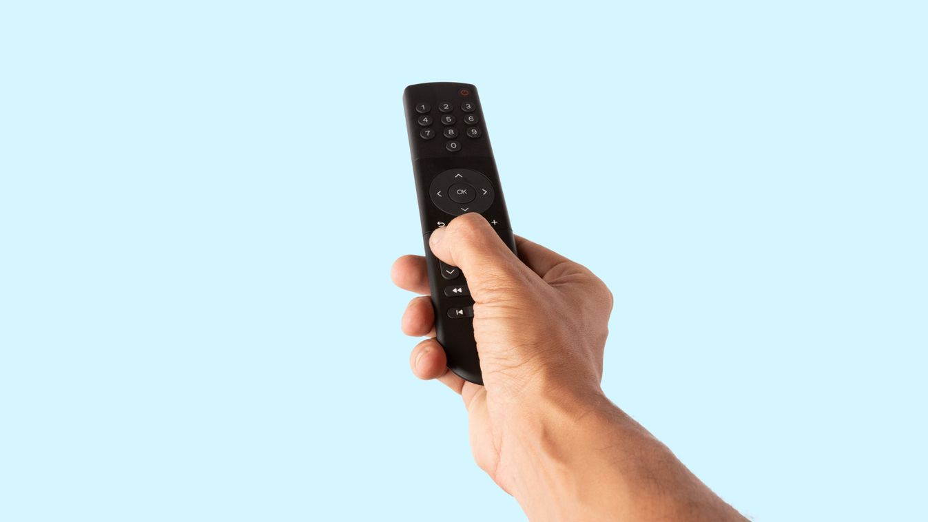 Male hand holding a tv remote controller isolated on cyan background cutout