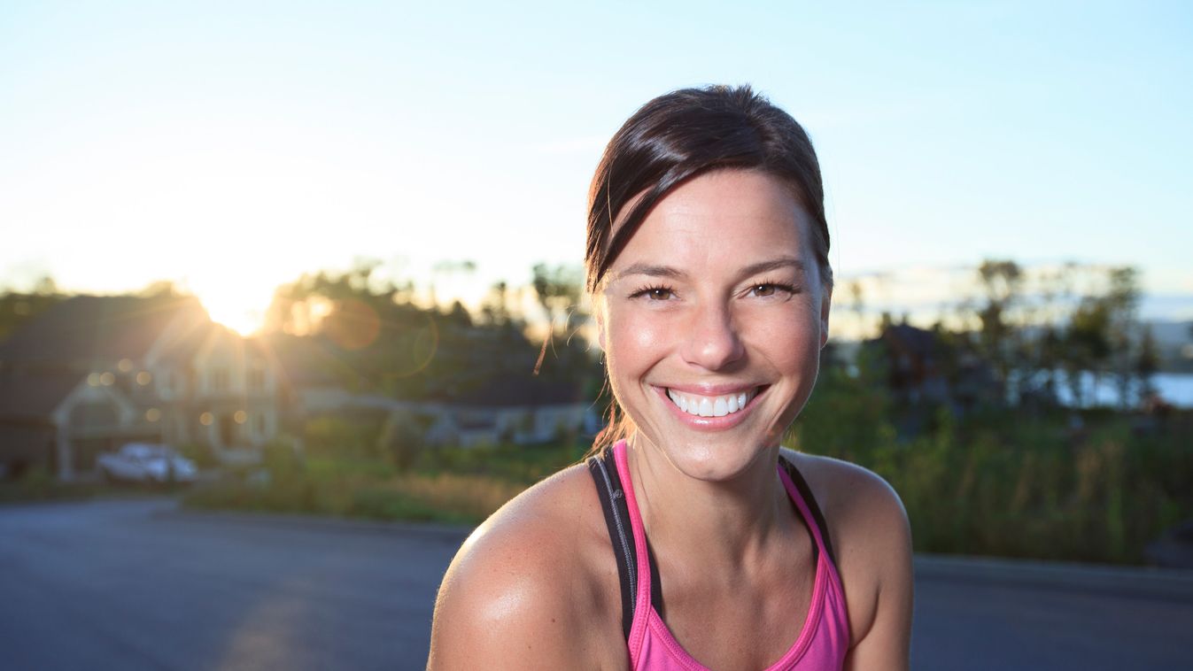 A woman jogging in a urban place with house in the background