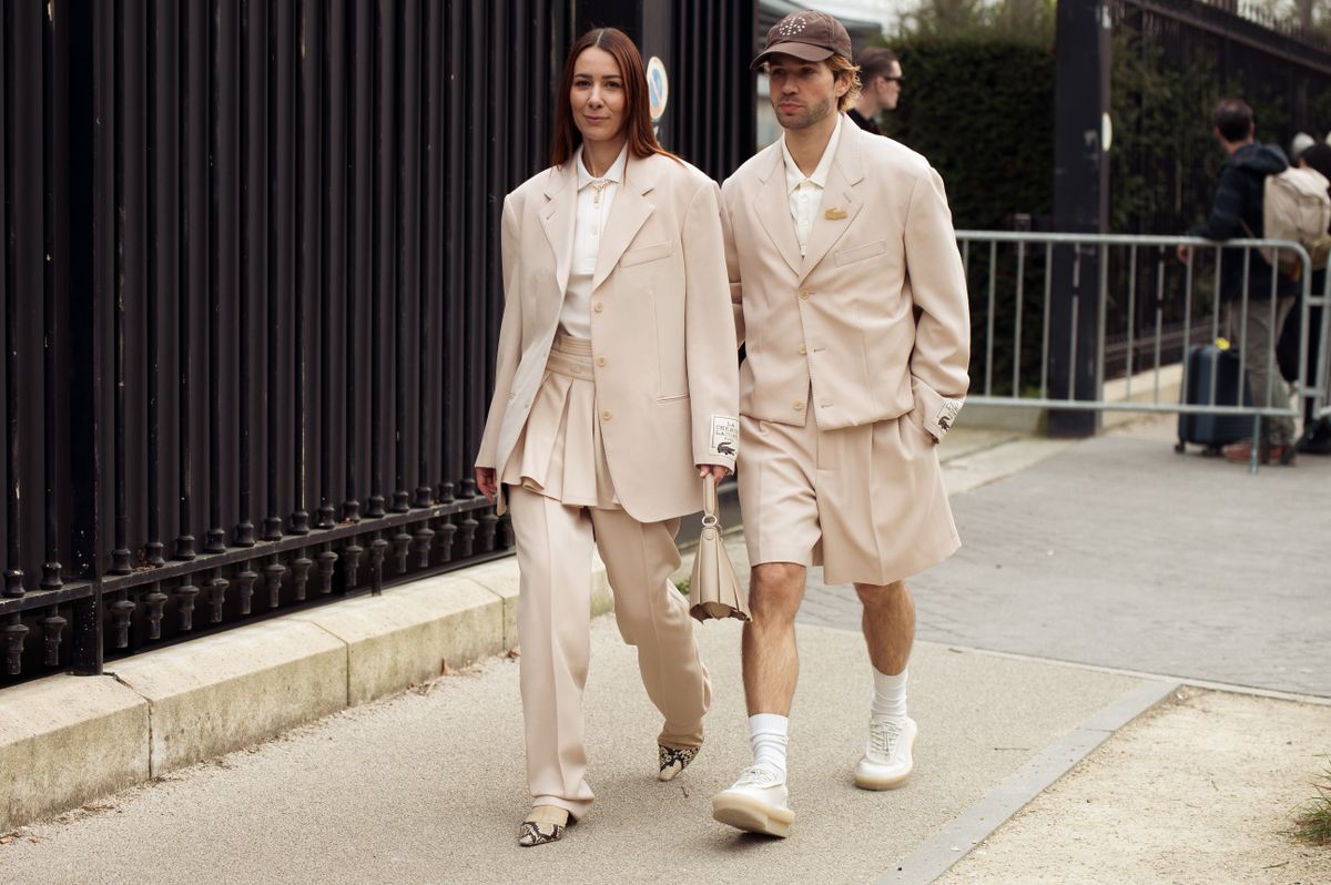 PARIS, FRANCE - MARCH 09: (L-R) Couple Alice Barbier wears beige suit, skirt, white polo shirt and a bag and Sebastien Roques wears cap, beige shorts, blazer outside the Lacoste fashion show during the Womenswear Fall/Winter 2025/2026 as part of Paris Fashion Week on March 09, 2025 in Paris, France. (Photo by Raimonda Kulikauskiene/Getty Images)