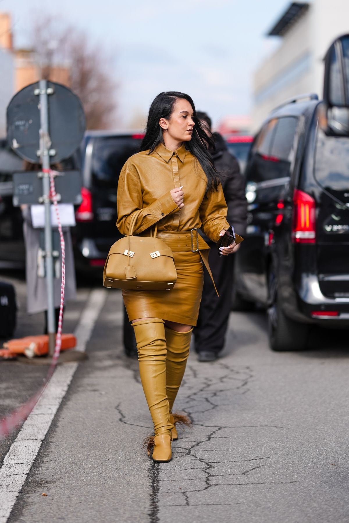 MILAN, ITALY - MARCH 01: A guest wears shiny light brown Ferragamo leather jacket, shiny light brown belted Ferragamo mini skirt, shiny light brown Ferragamo leather bag, light brown leather boots, outside Ferragamo, during the Milan Fashion week Women's Fall/Winter 2025-2026 on March 1, 2025 in Milan, Italy. (Photo by Edward Berthelot/Getty Images)