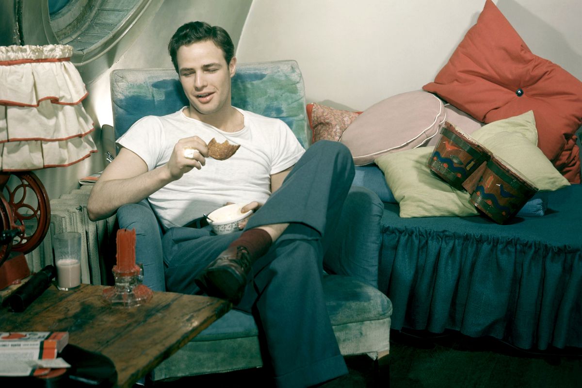 American actor Marlon Brando (1924 - 2004) sits in his bedroom eating breakfast in New York, New York, February 1955. (Photo by TPLP/Getty Images)