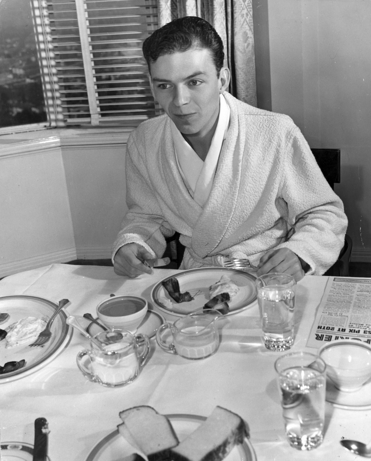 circa 1940:  A young Frank Sinatra in his dressing gown tucks into some bacon and eggs.  (Photo by Hulton Archive/Getty Images)