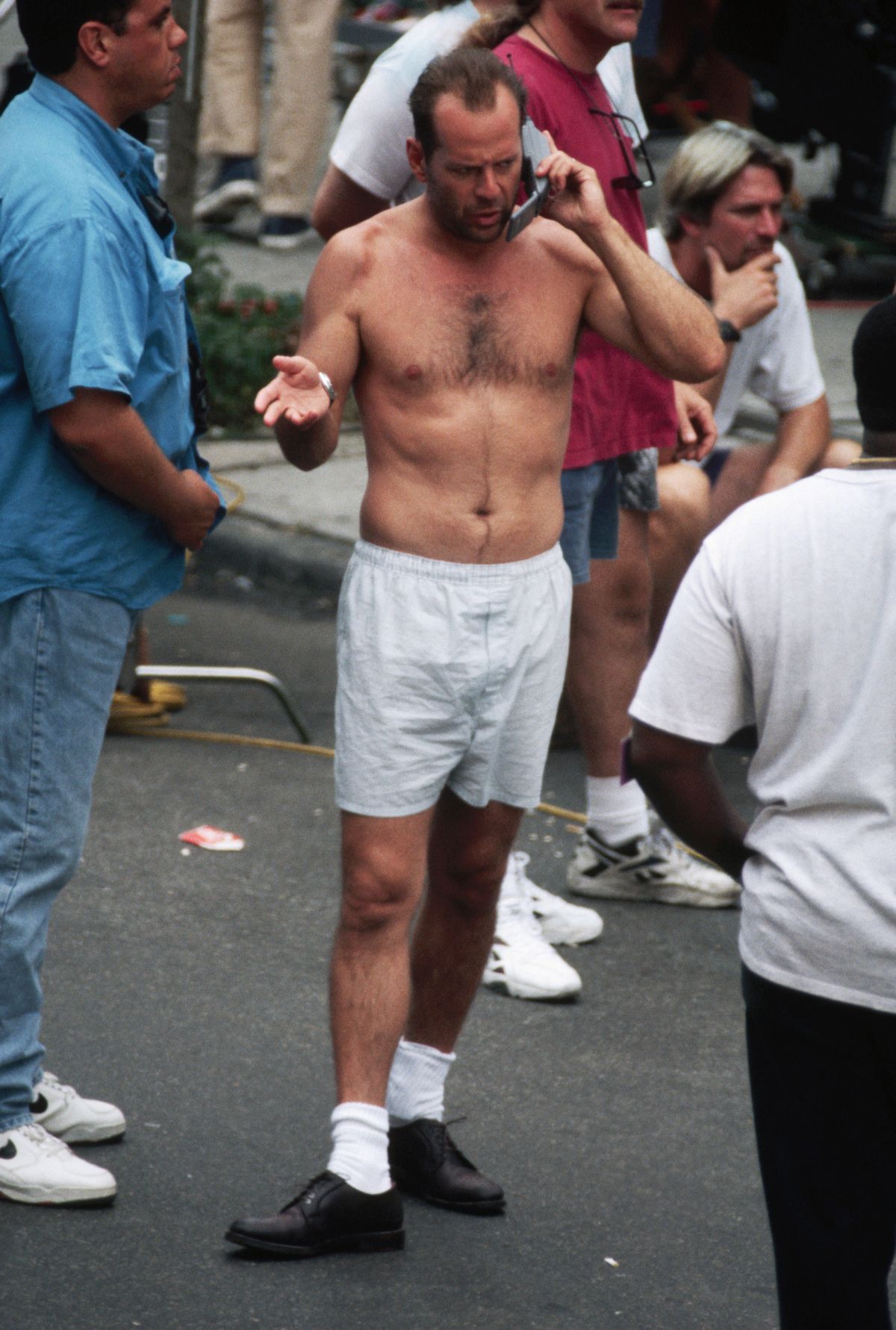 Bruce Willis talks on a cellular phone while standing on a street in boxer shorts on the set of Die Hard With a Vengeance.   (Photo by Mitchell Gerber/Corbis/VCG via Getty Images)