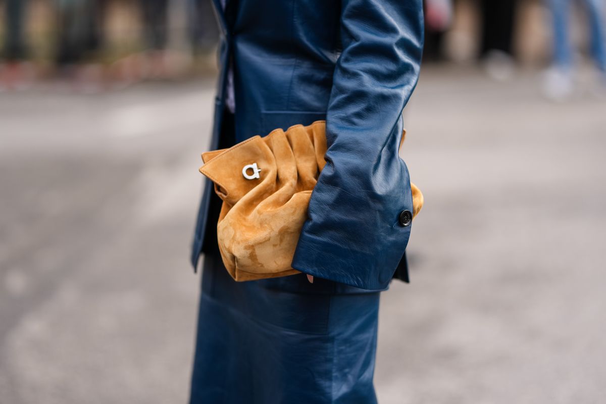 MILAN, ITALY - MARCH 01: A guest wears a light brown Ferragamo suede bag, outside Ferragamo, during the Milan Fashion week Women's Fall/Winter 2025-2026 on March 1, 2025 in Milan, Italy. (Photo by Edward Berthelot/Getty Images)