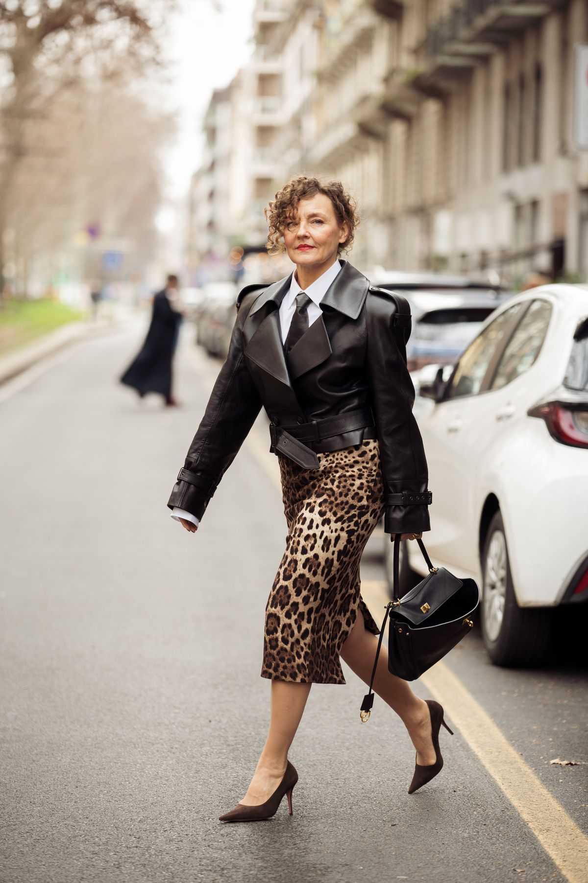 MILAN, ITALY - MARCH 01: Renia Jaz wears animal print midi skirt, black leather bag, white shirt, black leather tie and black leather jacket outside the Dolce & Gabbana fashion show during the Milan Fashion Week Womenswear Fall/Winter 2025/2026 on March 01, 2025 in Milan, Italy. (Photo by Raimonda Kulikauskiene/Getty Images)