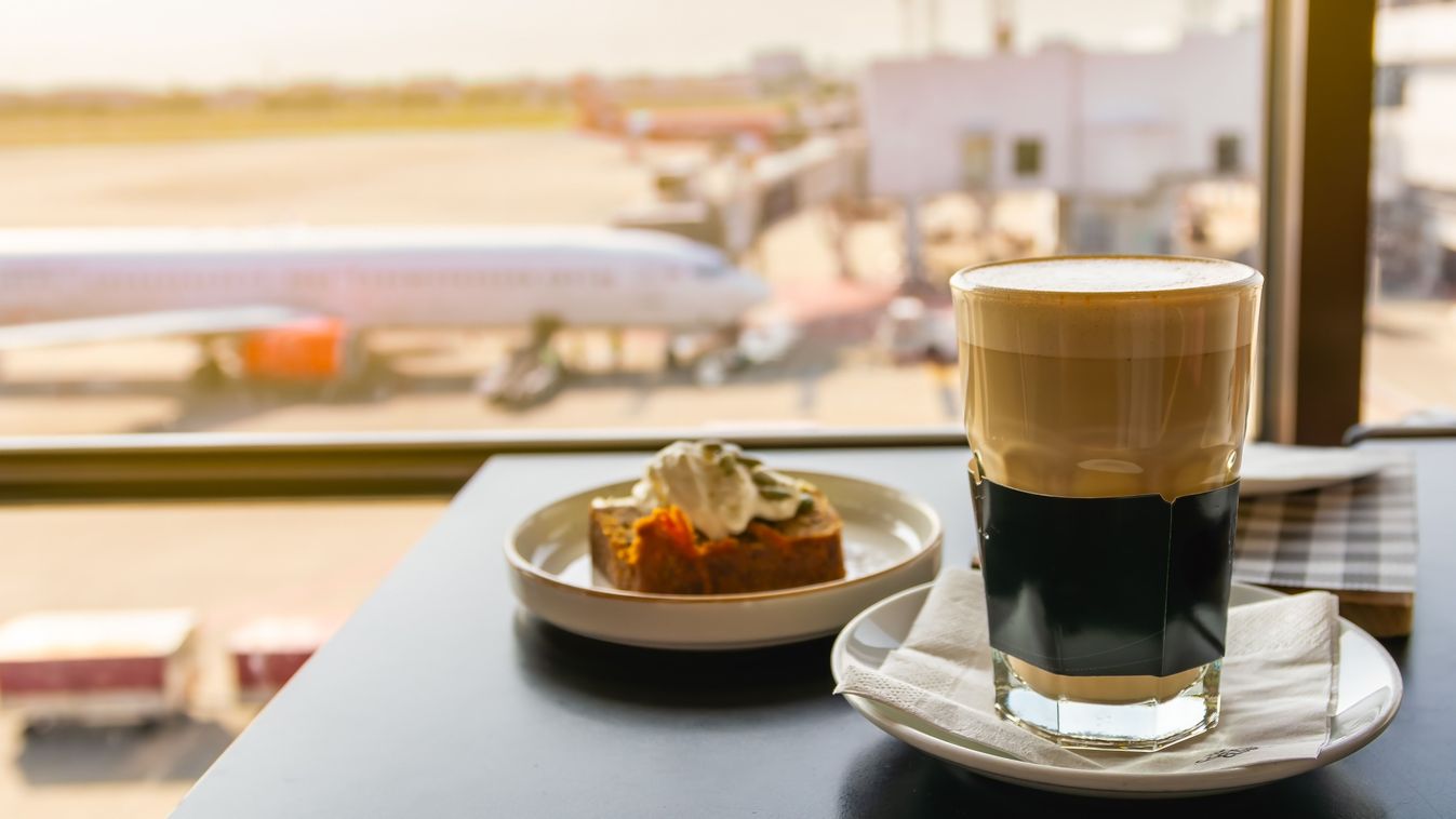 Hot coffee with breakfast at airport lounge, cup of hot cappuccino coffee in a glass cup on the table in the airport lobby, coffee and cake with plane background.