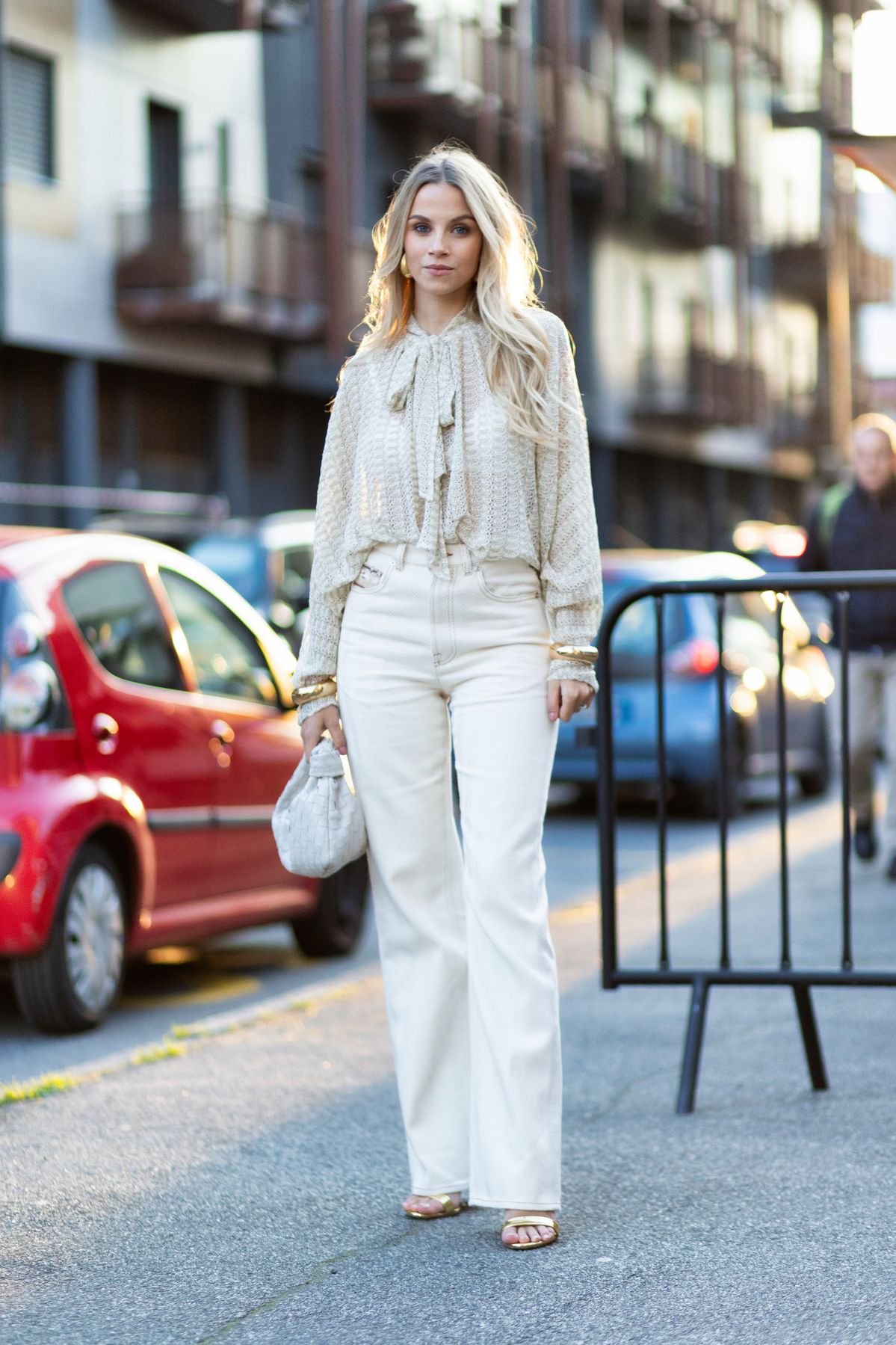 MILAN, ITALY - FEBRUARY 28: Simona Jakstaite wears gold heeled sandals, gold hoop earrings, a beige Missoni long sleeved shirt, gold bracelets, a white cream Bottega Veneta Jodie leather bag and Missoni high waist flared white ivory denim trousers outside Missoni show during the Milan Fashion Week Womenswear Fall/Winter 2025/2026 on February 28, 2025 in Milan, Italy. (Photo by Valentina Frugiuele/Getty Images)