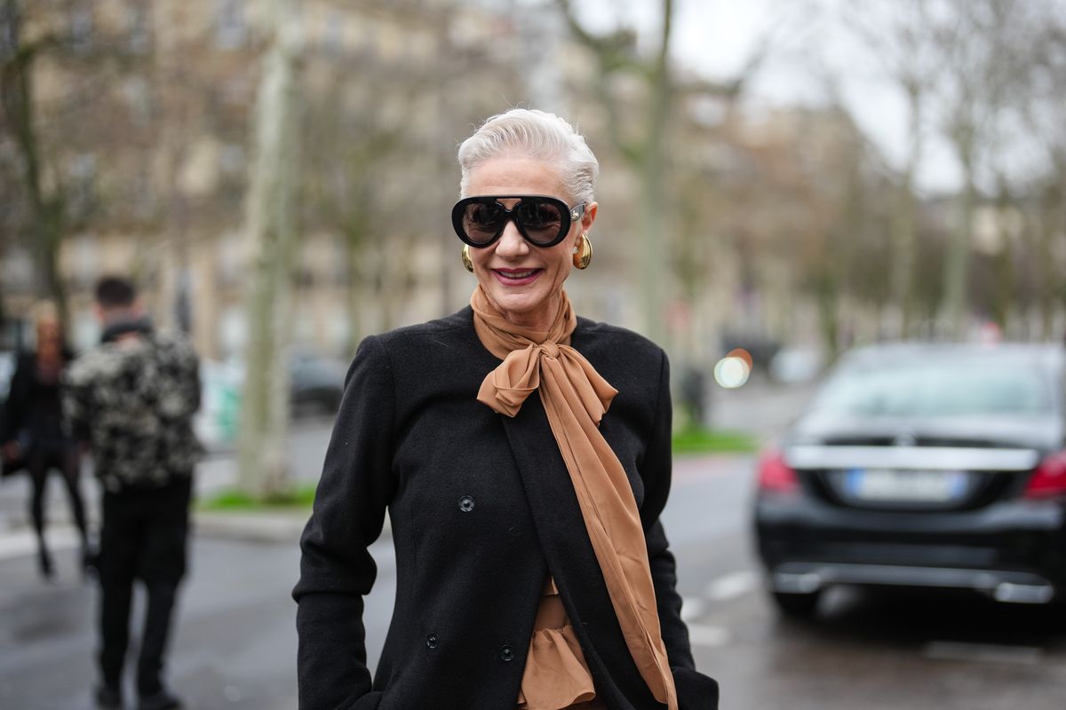 PARIS, FRANCE - JANUARY 30: A guest wears black sunglasses, a brown scarf, gold earrings, a black long coat, outside Juana Martin, during The Haute Couture Spring-Summer 2025 as part of  Paris Fashion Week on January 30, 2025 in Paris, France. (Photo by Edward Berthelot/Getty Images)