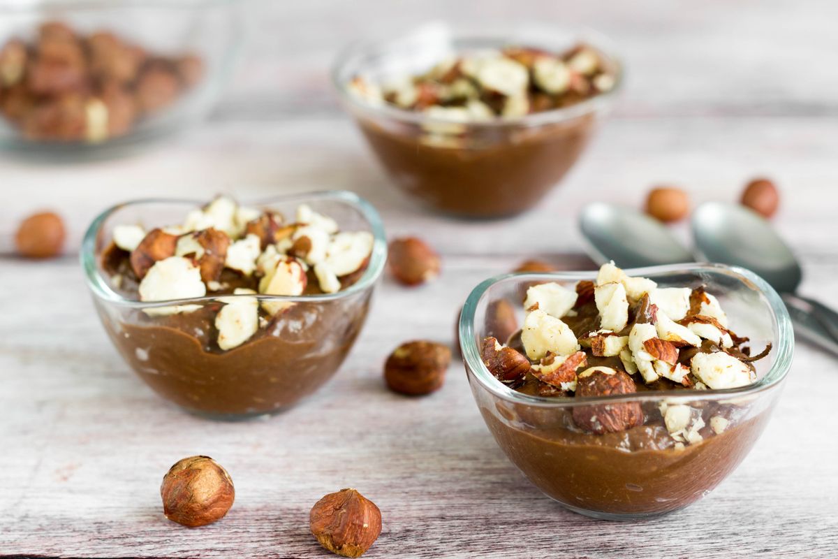 Vegan chocolate cream with avocado, cocoa and almond milk decorated with whole nuts