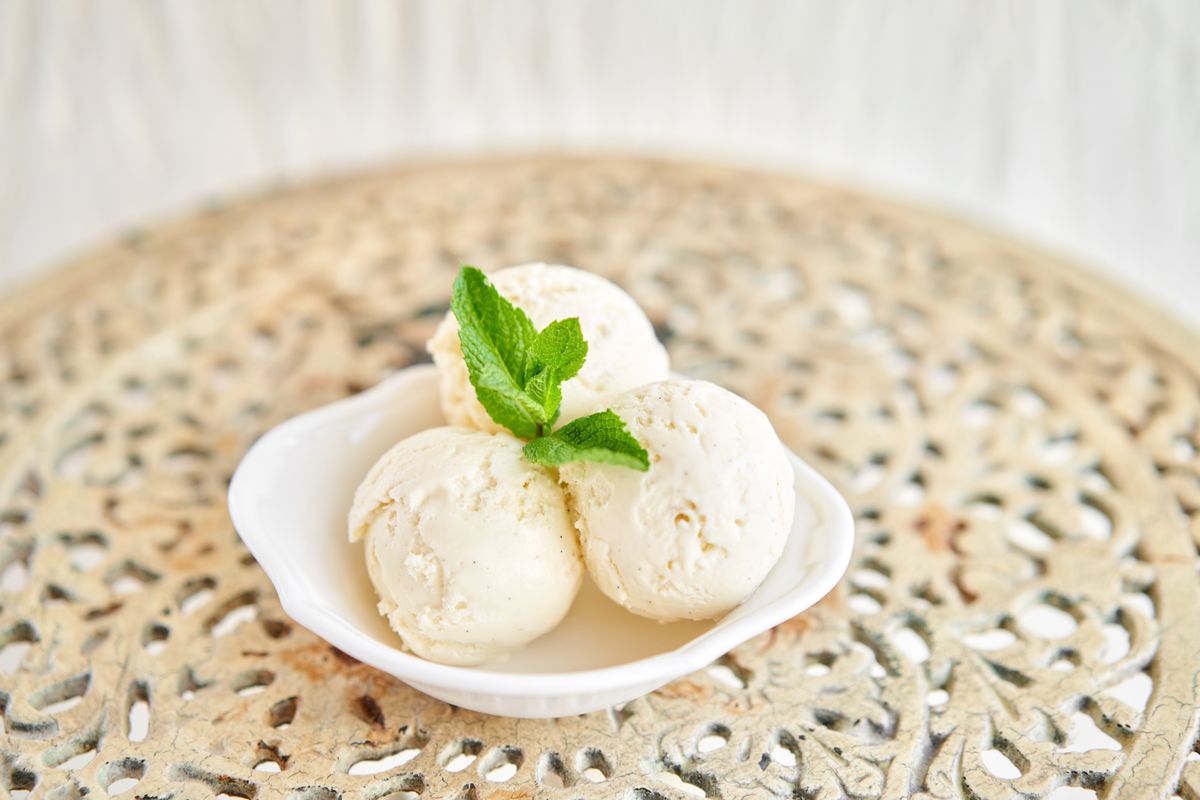 Italian gelateria. Vanilla ice cream with mint leaf. three balls in a white bowl on a vintage table.