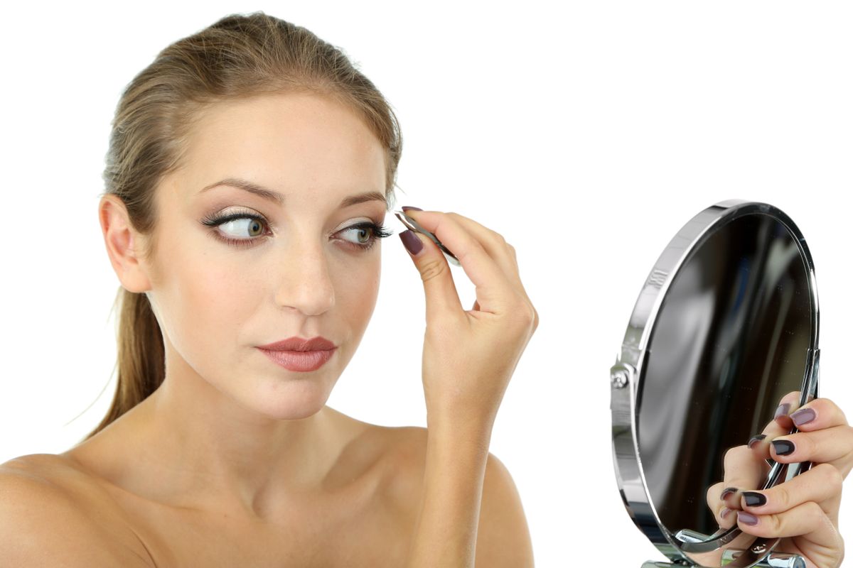 Young woman plucking eyebrows isolated on white