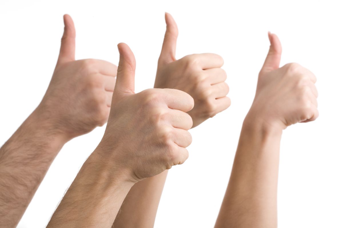Four hands with their thumbs raised up