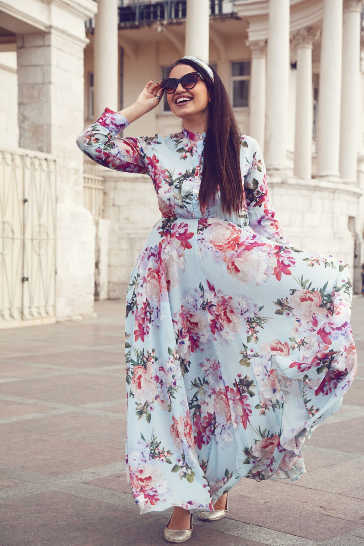 Plus size model wearing floral maxi dress posing on the city street. Young and fashionable overweight woman walking around town.
