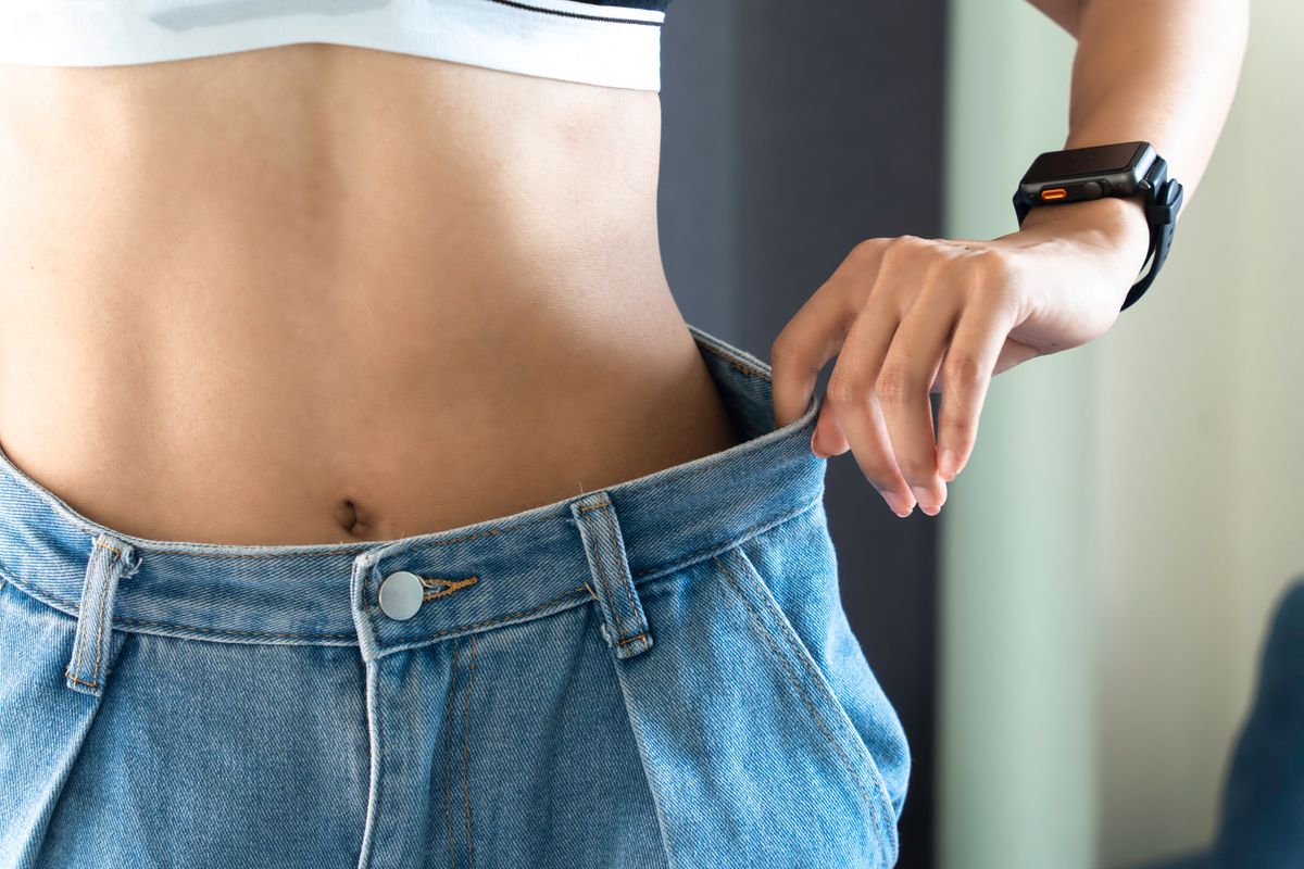 Young woman wearing white clothes showing loose pants after losing weight Ideas for exercise, fitness, food, gym, exercise, lifestyle and healthy ideas.