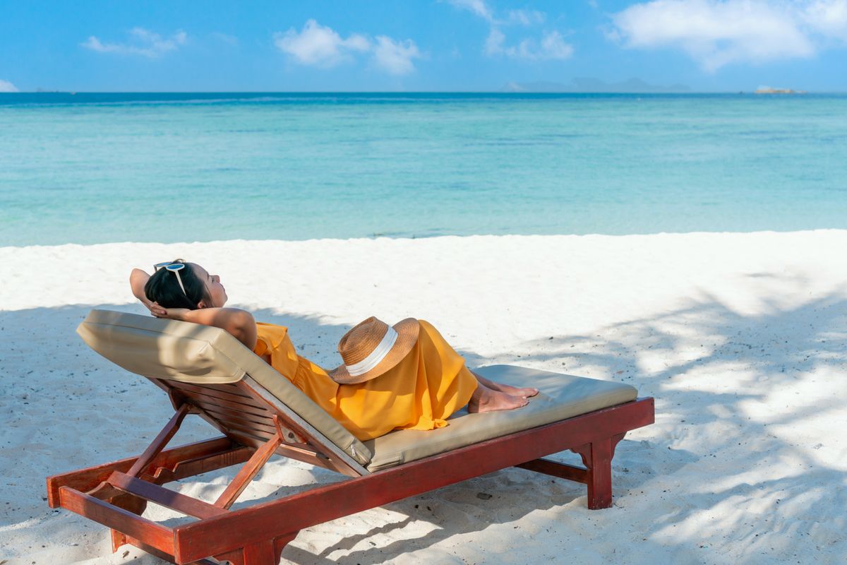 Happy Asian traveler woman relaxing on beach chair at tropical sandy beach Summer and vacation concept. Copy space