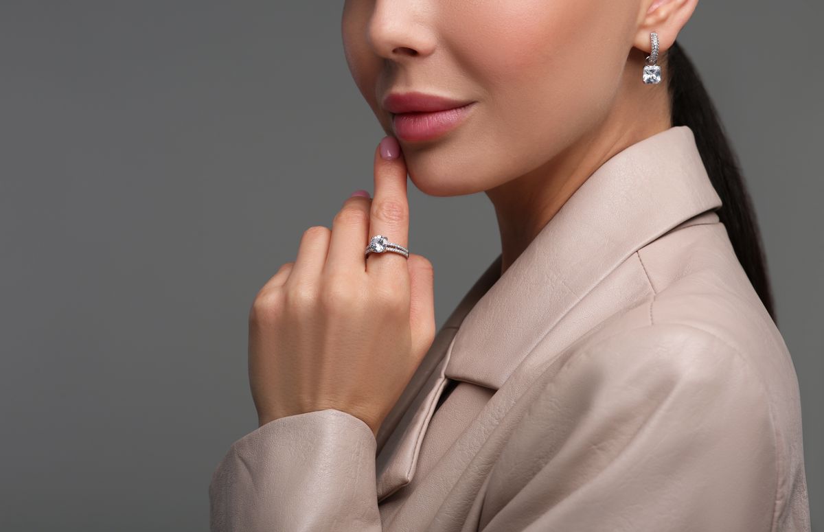 Young woman with elegant jewelry on dark grey background, closeup