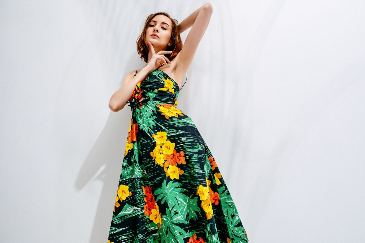 Fashion model, young woman posing with vogue summer leaves ,flower pattern dress, studio shot.