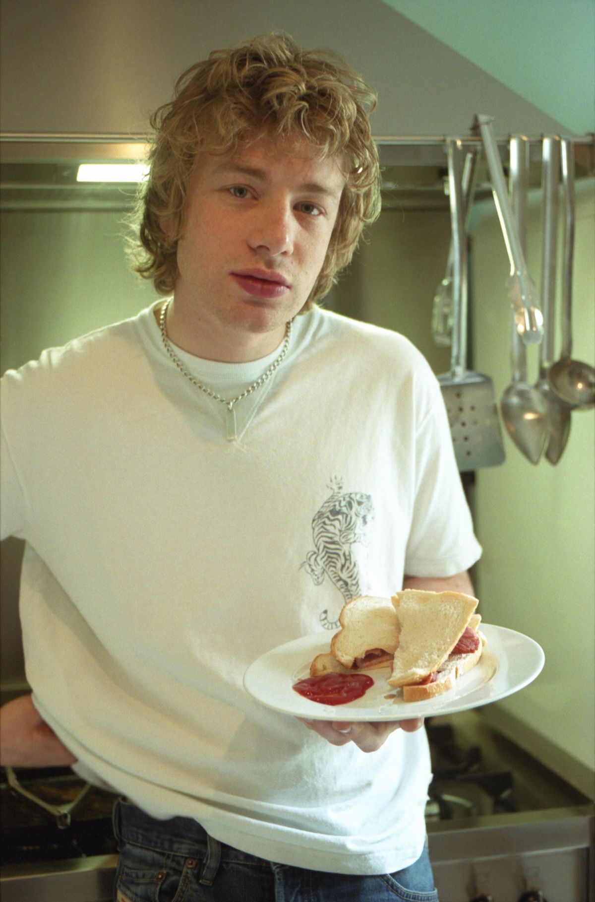 English celebrity chef Jamie Oliver poses for a portrait with a bacon sandwich on May 6, 1999 at his home in the UK. (Photo by Martin Godwin/Getty Images).