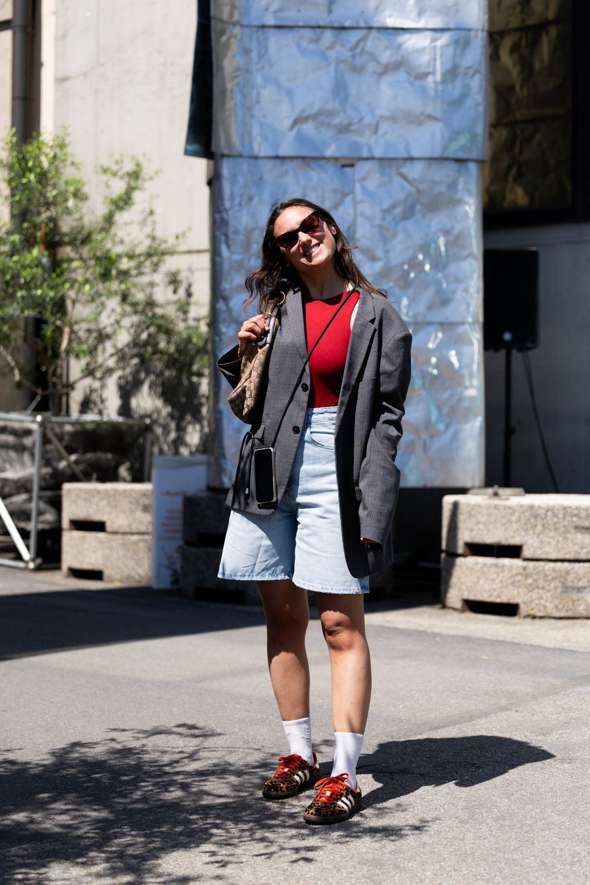 MILAN, ITALY - MAY 18: A guest wears brown sunglasses, a grey oversized blazer, a red body, light denim shorts, a Gucci bag, white socks and Adidas Samba OG leopard printed sneakers at East Market vintage fair on May 18, 2025 in Milan, Italy. (Photo by Valentina Frugiuele/Getty Images)