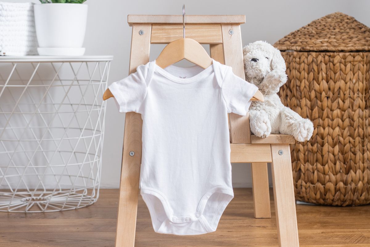 White baby short sleeve bodysuit mockup for presentation cute sublimation designs. Minimalistic photos of romper for toddlers in scandinavian interior with minimalistic decoration