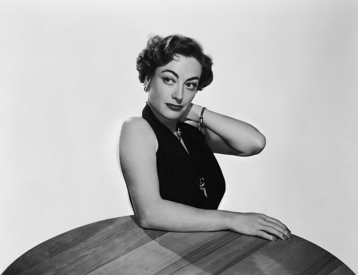 1950:  American film actress Joan Crawford (1908 - 1977) leaning on a table in a promotional picture for her latest film 'Harriet Craig'.  (Photo by Robert Coburn Jr./John Kobal Foundation/Getty Images)