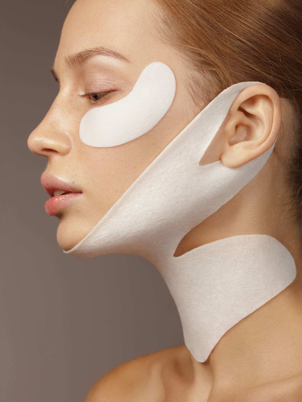 Portrait of young beautiful woman with skin care product on her face and neck