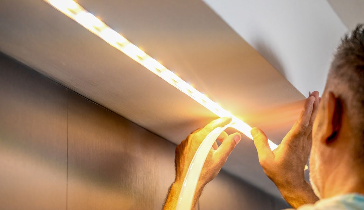 Installing led strip for lighting correctly on the surface of the Cabinet on the kitchen set.