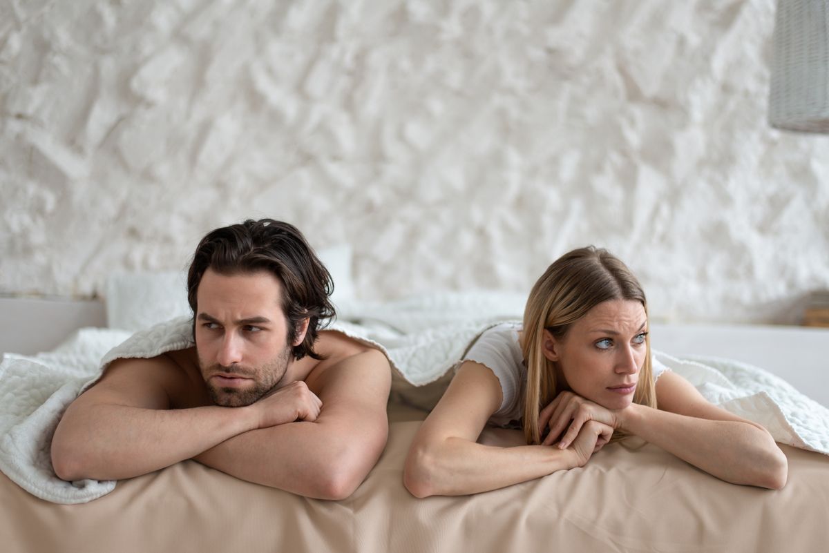 Sexual problems, relationship crisis. Stressed young couple lying in bed, overwhelmed with family difficulties, not speaking after conflict, suffering from erectile dysfunction or lack of libido