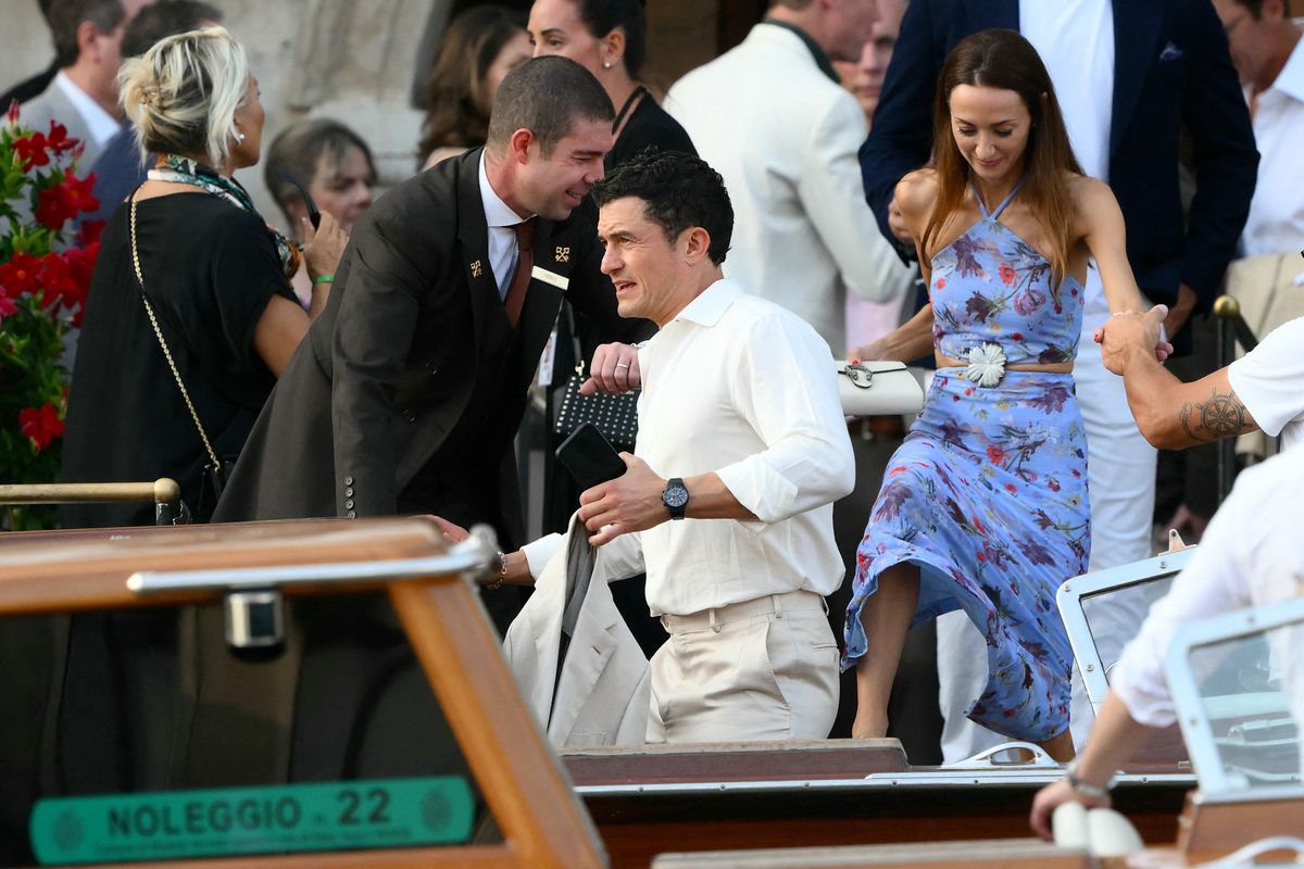 British actor Orlando Bloom and guest get on a taxi boat at the Gritti Palace Hotel ahead of the wedding of Amazon's founder Jeff Bezos with Lauren Sanchez in Venice on June 26, 2025. Celebrities in superyachts sail into Venice this week for the three-day wedding party of Amazon tycoon Jeff Bezos and Lauren Sanchez, despite irate locals who say the UNESCO city is no billionaire's playground. The tech magnate and journalist have reportedly invited about 200 guests to their multi-million dollar nuptials in the Italian city, which are expected to kick off on June 26 and end Saturday with a ceremony at a secret location. (Photo by Marco BERTORELLO / AFP)