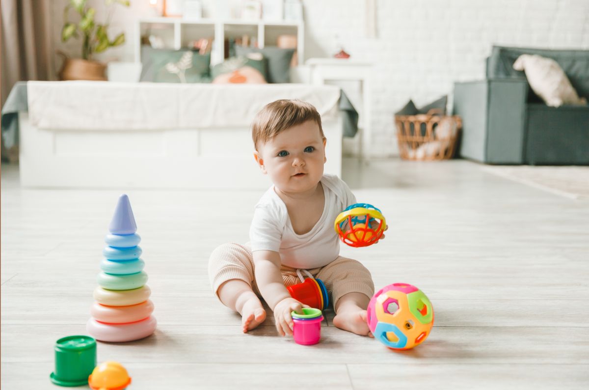 baby 6-9 months old playing with a colorful rainbow toy pyramid sitting in a white sunny bedroom. Toys for small children. Children's interior. A child with an educational toy.