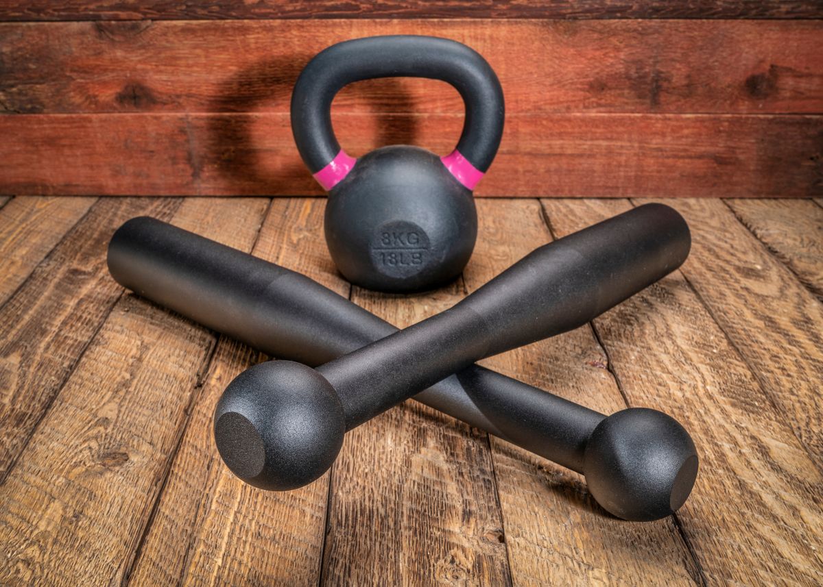 pair of heavy steel Indian clubs and a small iron kettlebell against rustic, weathered wood background - functional fitness concept