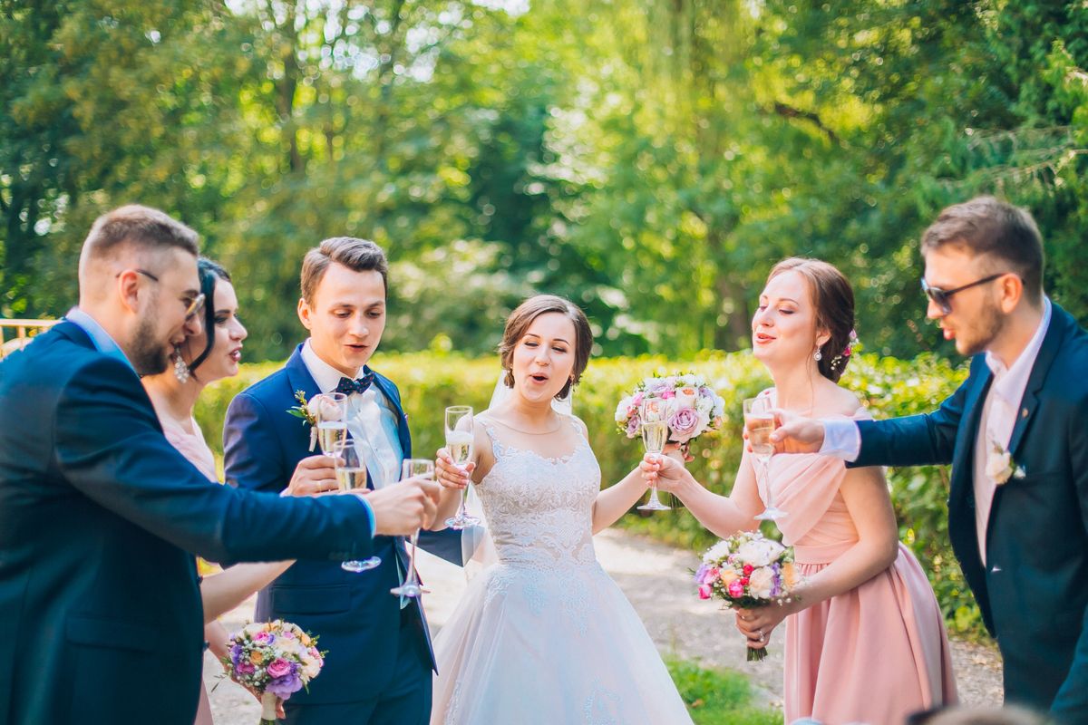 Bride and groom with happy groomsmen and bridesmaids having fun and popping champagne, newlyweds wedding hilarious moment. Funny momen. Crazy wedding people.