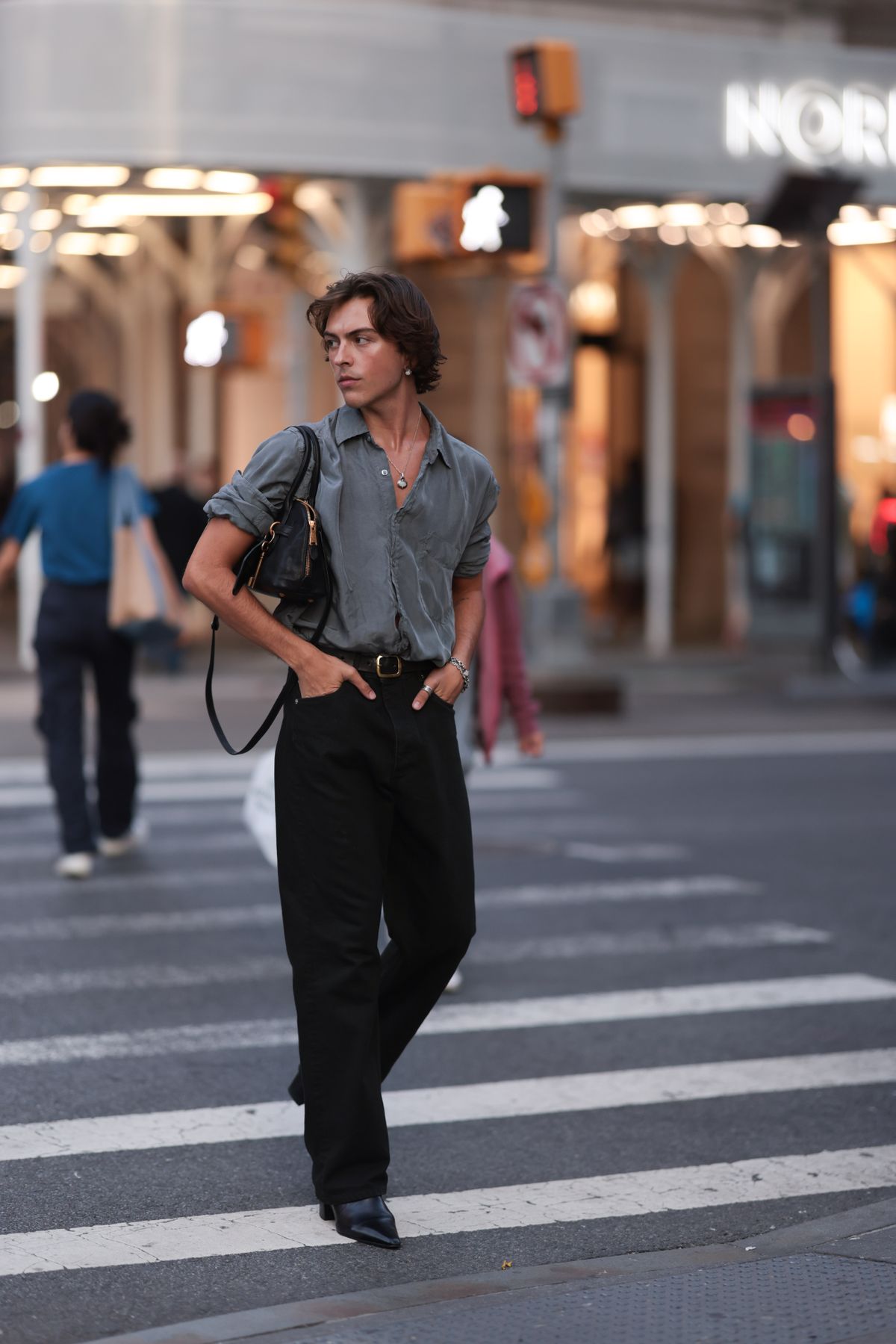 NEW YORK, NEW YORK - SEPTEMBER 04: Tyler Omeed Mazaheri is seen wearing silver earrings with white round stones, a fine silver necklace with a matching pendant, a grey shirt with rolled-up sleeves, a rectangular black leather bag with gold details, a silver rings, two silver bracelets, black straight-legged jeans, a black leather belt with a gold buckle, and pointed black leather heeled boots before the Jacquemus Boutique Store Opening during the New York Fashion Week on September 04, 2024 in New York City. (Photo by Jeremy Moeller/Getty Images)