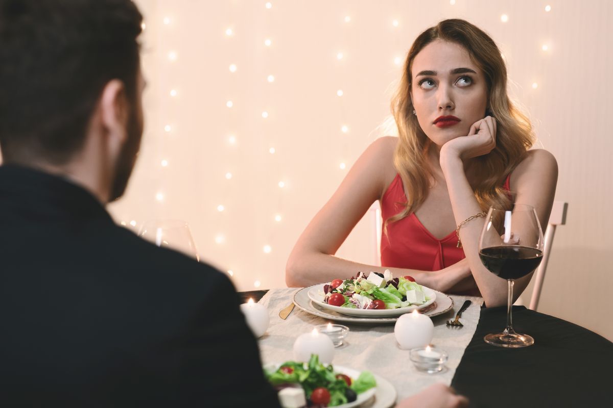 Unsuccessful Date. Young woman feeling bored at dinner in restaurant, looking away with disappointed face expression, selective focus
