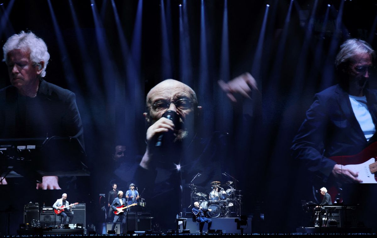 British singer Phil Collins (C) performs on stage during "The last domino" tour of the British rock band Genesis with English musicians and partners Tony Banks (L) and Mike Rutherford (R), at the Paris La Defense Arena, in Nanterre, northeastern France, on March 16, 2022. (Photo by THOMAS COEX / AFP)