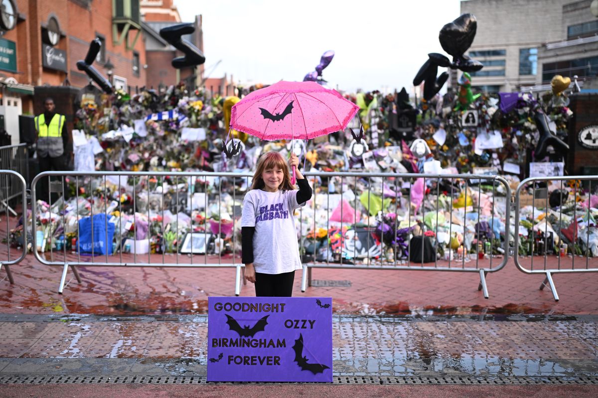 BIRMINGHAM, ENGLAND - JULY 30: Eliza Finn-O’Shea of Birmingham poses in front of tributes prior Ozzy Osbourne's funeral cortege is set to travel through his home city of Birmingham on July 30, 2025 in Birmingham, England. The Black Sabbath frontman passed away on July 22nd at the age of 76. His death occurred just a little over two weeks after his final live performance at the 'Back to the Beginning' concert in his hometown of Birmingham. (Photo by Leon Neal/Getty Images)