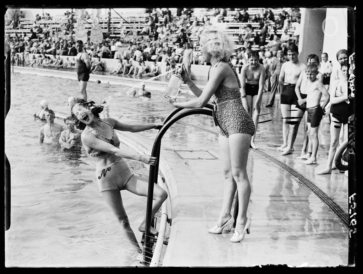 UNITED KINGDOM - JANUARY 30:  Water fight at an outdoor swimming pool, 1937. A photograph of a water fight at an outdoor pool in Morecambe, Lancashire, taken by Saidman for the Daily Herald newspaper on 1 September, 1937. One woman shoots another with water from a soda syphon - as she attempts to climb out of the pool. Outdoor swimming pools became popularly known as 'lidos' in the 1930s - and proved to be very popular during the first half of the 20th century in Britain. This photograph has been selected from the Daily Herald Archive, a collection of over three million photographs. The archive holds work of international, national and local importance by both staff and agency photographers.  (Photo by Daily Herald Archive/SSPL/Getty Images)