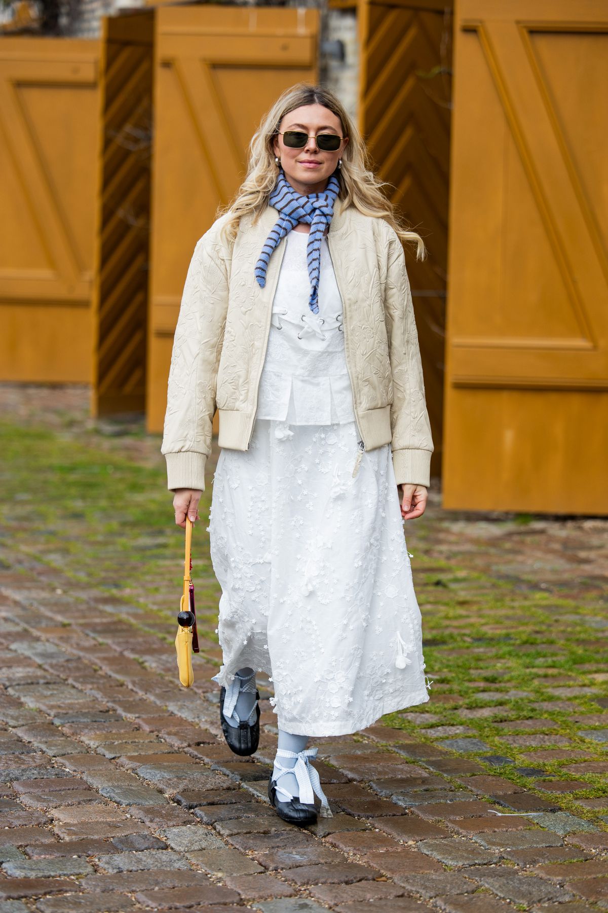 COPENHAGEN, DENMARK - JANUARY 30: Elise Bak wears beige jacket, scarf in blue, white skirt, shirt, yellow bag outside Munthe during the Copenhagen Fashion Week Autumn/Winter 2025 on January 30, 2025 in Copenhagen, Denmark. (Photo by Christian Vierig/Getty Images)