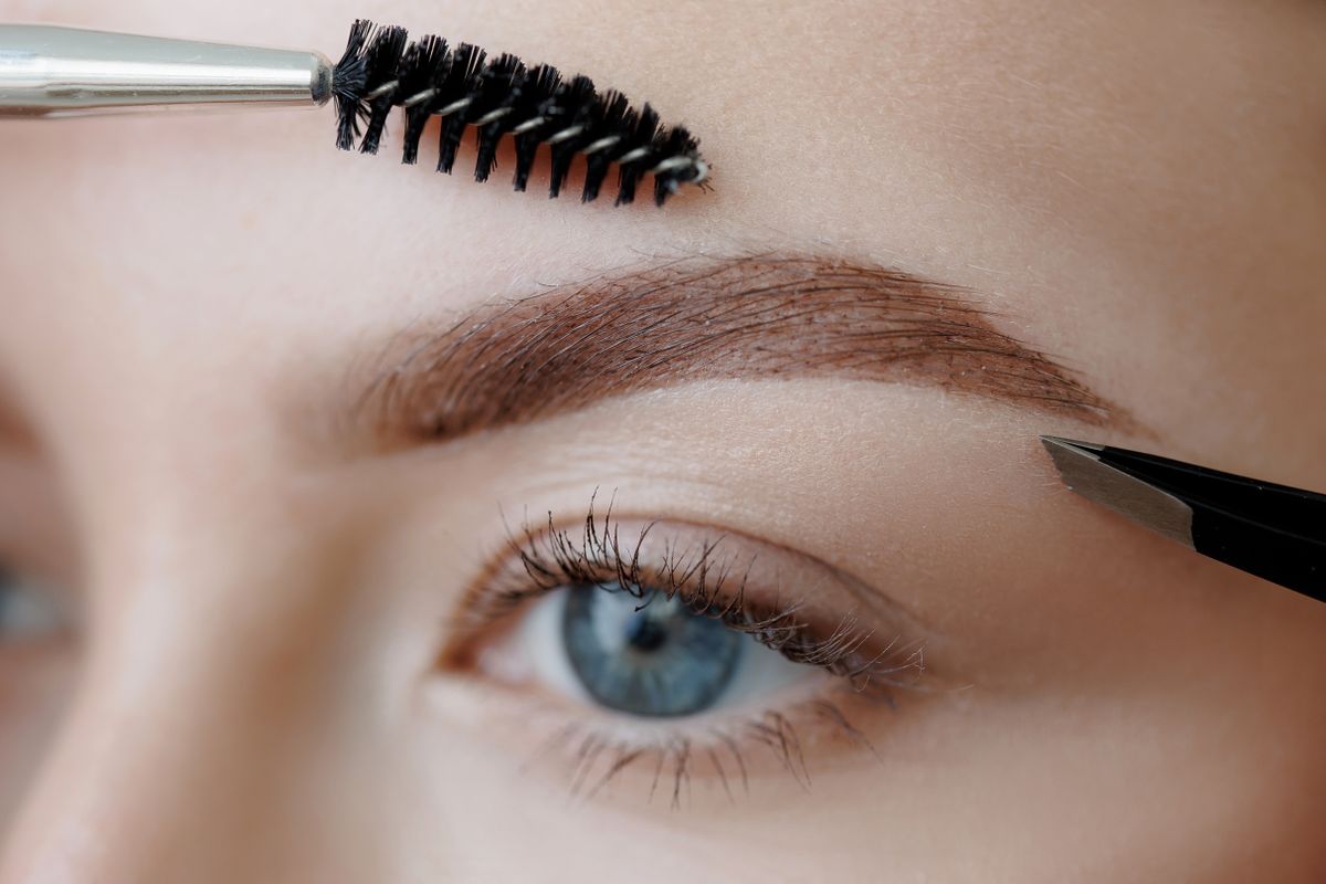 Eyebrow tinting correction macro photo, brush and tools enhance caucasian young female brows.