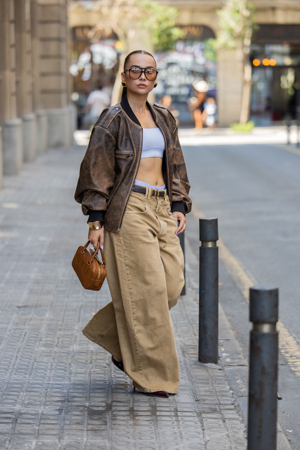 BARCELONA, SPAIN - AUGUST 16: Anna Wein wears beige jeans ZARA, brown leather jacket DUCIE LONDON, sunglasses YSL, brown bag MIU MIU, heels ZARA, bracelet on August 16, 2025 in Barcelona, Spain. (Photo by Christian Vierig/Getty Images)