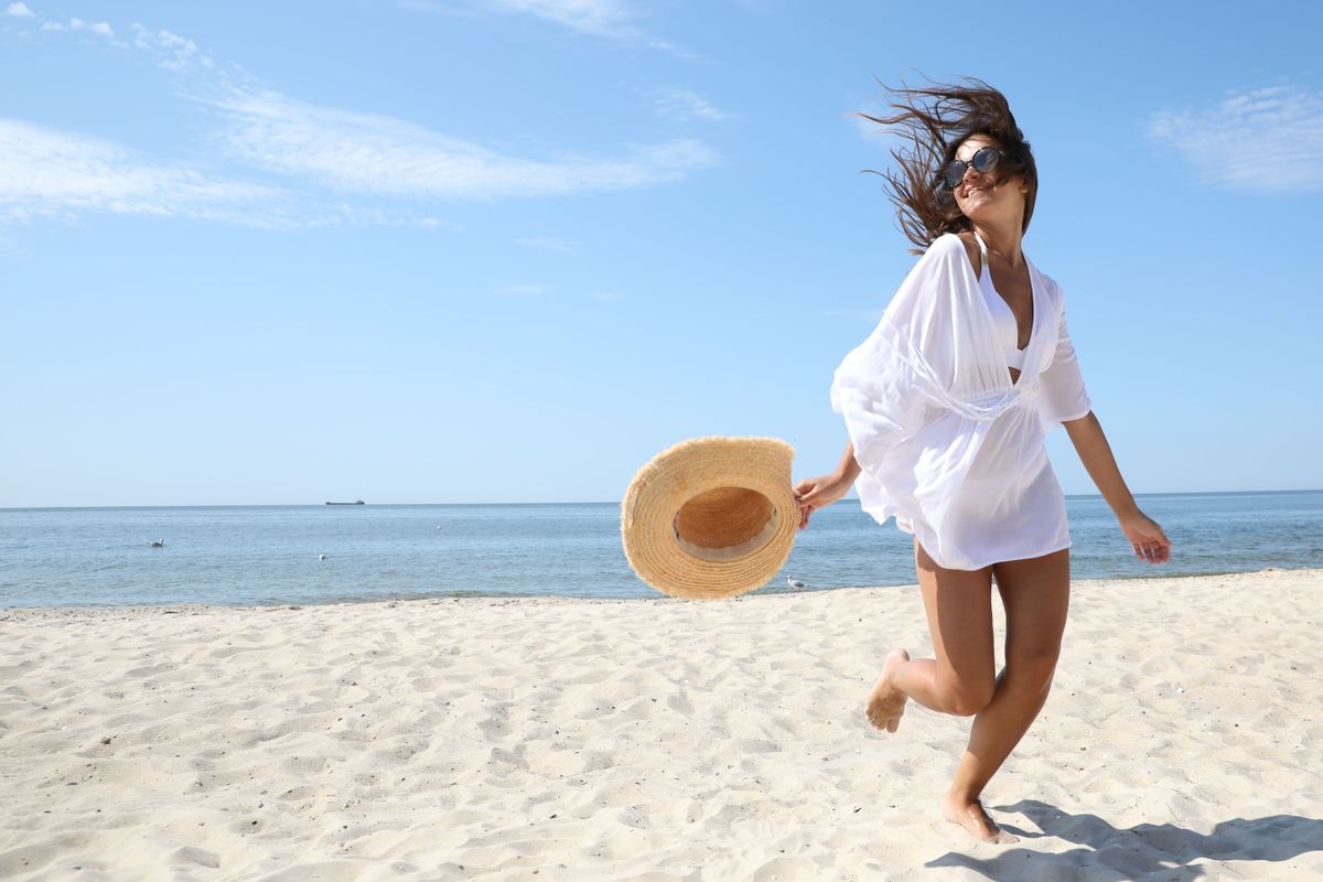 Young woman with beautiful body on sandy beach. Space for text