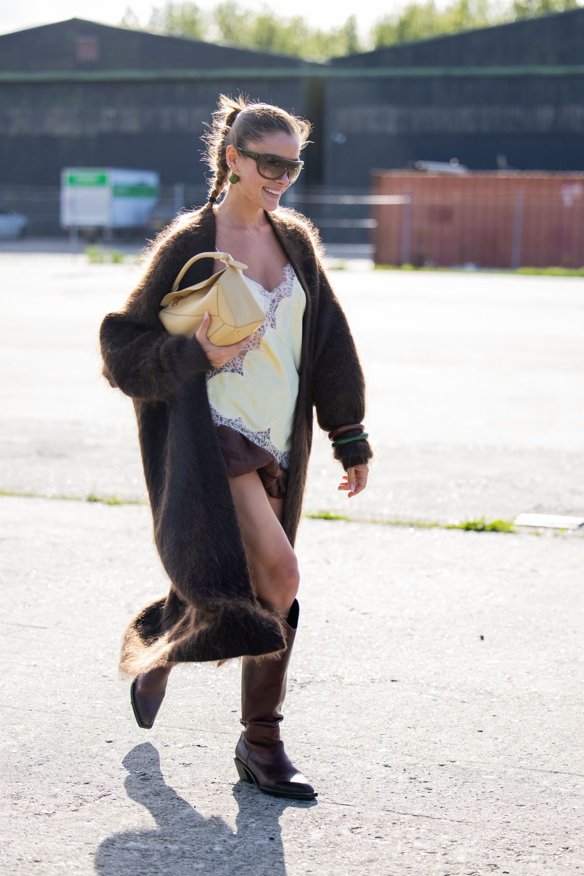 COPENHAGEN, DENMARK - AUGUST 05: A guest wears brown cardigan, butter yellow laced dress, brown skirt, boots, bag outside Rolf Ekroth during Copenhagen Fashion Week day two on August 05, 2025 in Copenhagen, Denmark. (Photo by Christian Vierig/Getty Images)