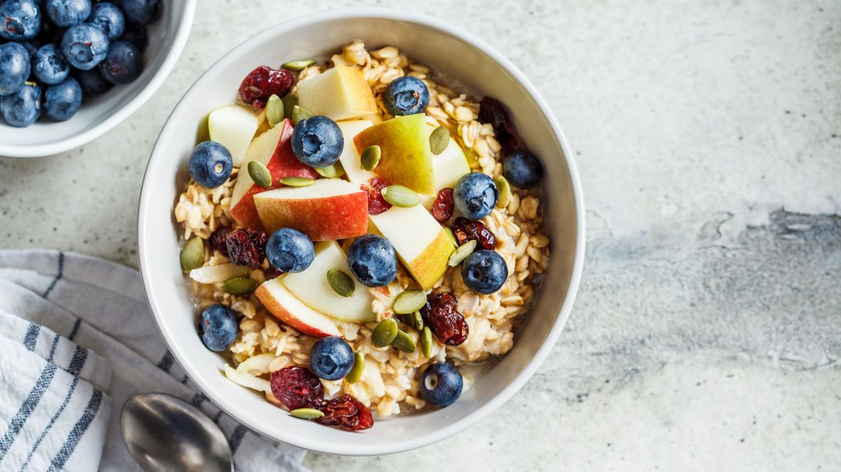 Bircher muesli or overnight oatmeal with apple, banana and blueberries in a gray bowl, copy space.
