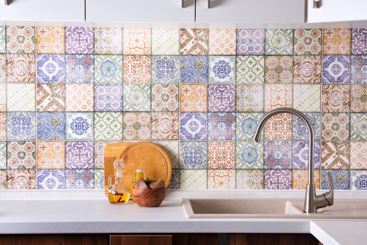 Shiny stainless steel faucet with chrome water tap, stone sink and wooden bowls with olive olives on a background of colored old tiles. Kitchen interior
