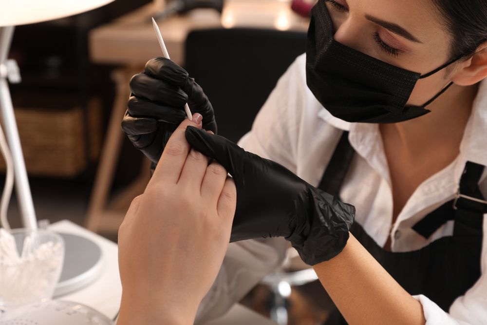 Professional manicurist working with client in salon, closeup. Beauty services during Coronavirus quarantine