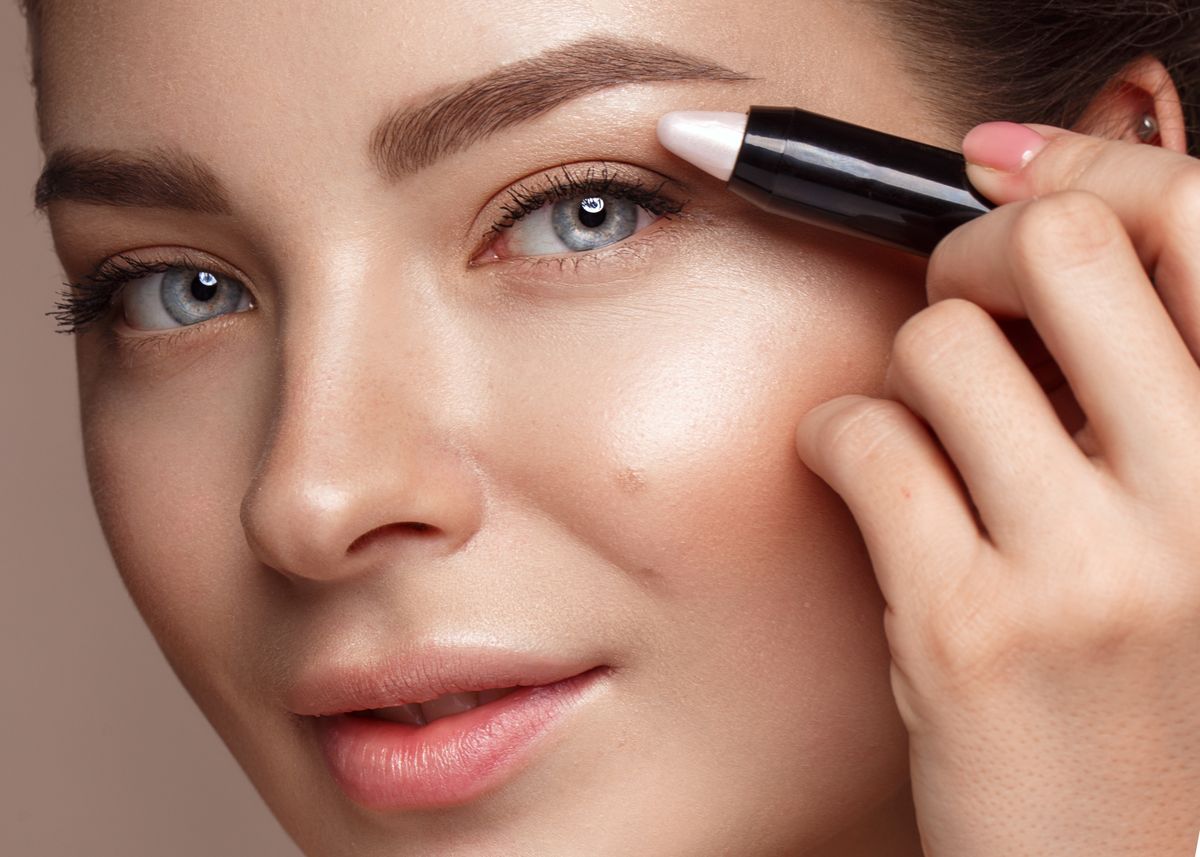 Beautiful young girl with natural nude make-up and highlighter pencil. Beauty face. Photo taken in studio