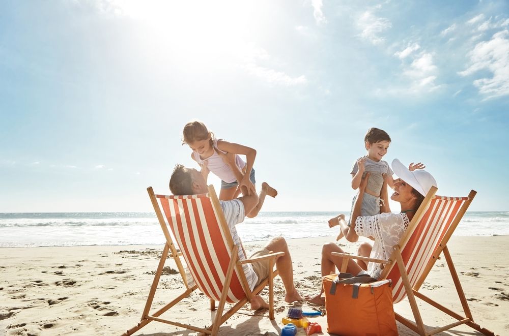 nyaralás Family, beach and kids relax chair vacation adventure, bonding and play game together on tropical summer. Parents, children and excited of ocean island, energy and sunshine travel in Greece