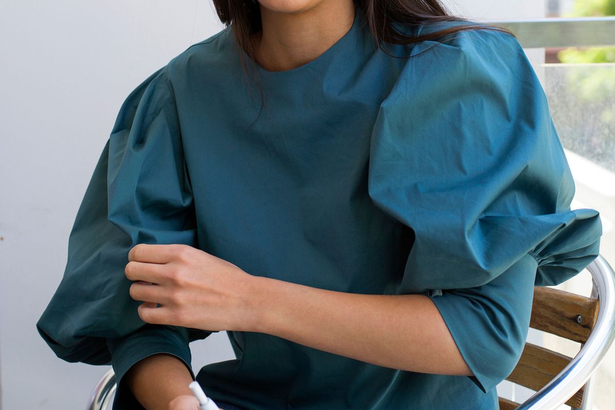 Close up fashion detail, young woman wearing a dark teal puff sleeve blouse